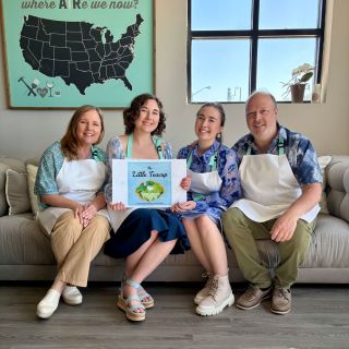 Family group photo sitting on a couch in a studio displaying self-published children's book