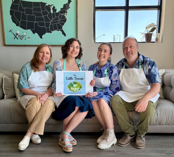 Family group photo sitting on a couch in a studio displaying self-published children's book