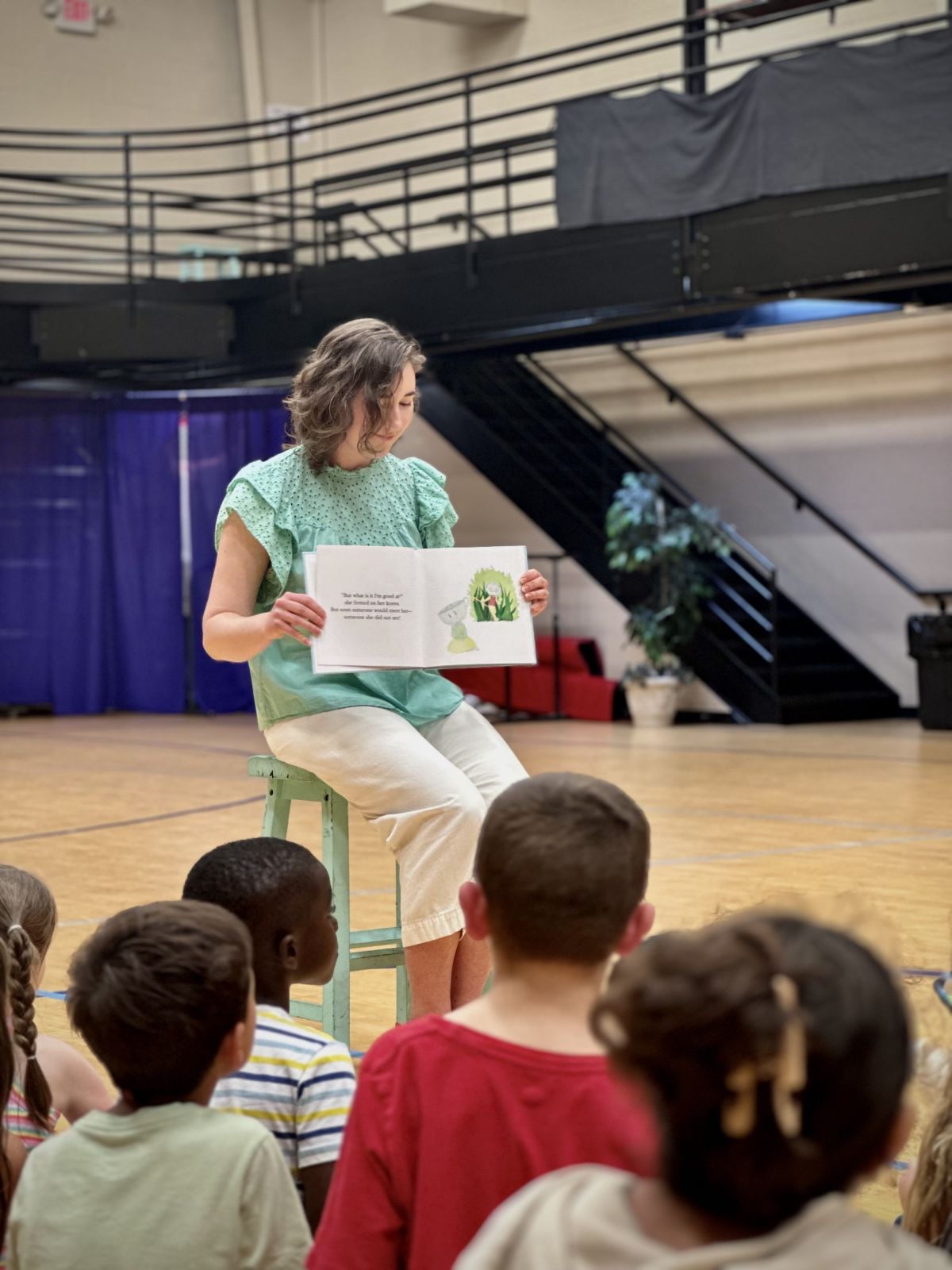 children's book author reading Christian picture book to students in school gym